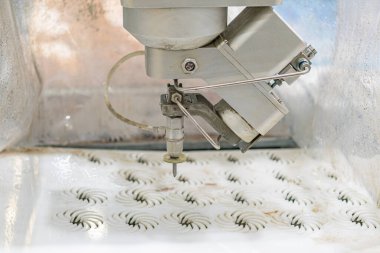 Endüstriyel aydınlatma altında, metalik makinelerin ve sessiz çevrelerin zeminine plastik ya da benzeri malzemeler damgalayan endüstriyel bir robotun yakın plan çalışması.