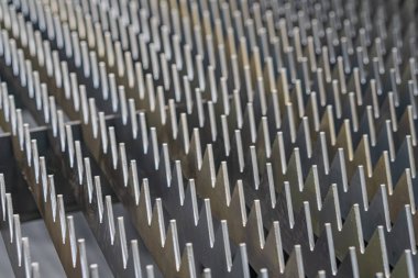 Gri ve metalik tonlarda gösterilen ve tekrarlanan küçük projeksiyon ya da diş desenleri ile endüstriyel mekanizma bileşeninin yakın görüntüsü