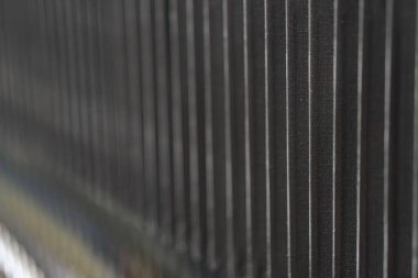 İç mekandaki yayılmış ışıklandırmanın altında dikey çıkıntıları ve yatay dikişleri olan desenli metalik nesnelerin yakın plan fotoğrafı.