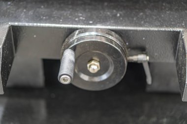 Siyah, çizik bir yüzey üzerinde endüstriyel ekipman bileşenine yakın çekim merkezi merkezli dairesel metal parçası ve çeşitli metalik elementlerle çevrili düz başlı vida.