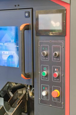 Çoklu kırmızı ve yeşil düğmeli bir endüstriyel kontrol panelinin yakın görüntüsü, mavi grafik arayüz ekranı, saplarında turuncu aksanlar, modern tasarım, kapsamlı açı, hatta ışıklandırma, vivi
