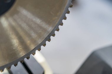 Keskinlik ve dayanıklılık için tasarlanmış sayısız keskin dişlere sahip endüstriyel testere bıçağının yakın çekimi bulanık bir arka plana karşı metalik gölgeler tarafından yönetilir.