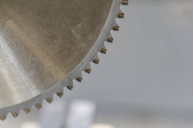 Yıpranmış, dişleri ya da tırtıklı metalik bir nesnenin yakın plan görüntüsü, muhtemelen testere ya da çim biçme makinesi gibi inşaatlarda kullanılıyor, endüstriyel arka planda yapay ışıklandırma ile kurulmuş metinler yok.