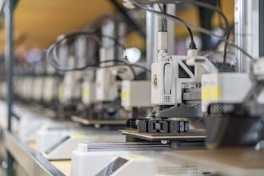 Robotik silahlar, kontrol panelleri, elektrik kabloları beton döşeme, açık renkli duvarlar, hatta üstten aydınlatma gibi otomatik üretim ekipmanlarıyla endüstriyel bir ortam.