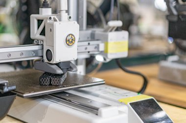 Endüstriyel 3D yazıcının yakın görüntüsü, ürünü işleyen büyük bir otomatik makine ile makine görünür mekanik bileşenlere ve sarı bir kontrol elemanına ve taşıyıcı bant veya mo 'ya sahiptir.