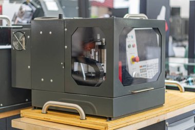Geniş bir CNC yönlendirici ya da kesme cihazı, gri ve mavi renk paleti, hatta ışıklandırma, hafifçe yükseltilmiş kamera açısı olan endüstri ortamları