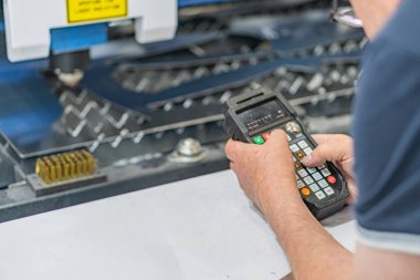 Metalik makinelerde endüstriyel lazer kullanan kişi, koyu renk gömlek, göreve odaklan, metal dişliler veya eşyalar, çelik alaşımlı alaşımlı makine, yapay ışıklandırma, birden fazla ışık kaynağının gölgeleri,