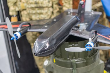 Mavi pervaneli siyah ve gümüş bir Ukrayna FPV İHA 'sının yakın plan görüntüsü, endüstriyel bir ortamda, insansız hava aracının görünür vidaları ve bağlayıcıları var, modüler yapısını gösteriyor.