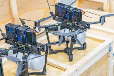 İki Ukrayna sanayi kuadkopteri kargo gövdeli, tahta bir yüzeye yerleştiriliyor. Ön taraftaki şeffaf kubbeler iç bileşenlerin görüntülerini sunuyor.