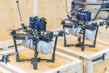 Tahta sandıkların üzerinde birbirine benzeyen üç Ukrayna FPV İHA 'sının yakın görüntüsü, her birinin gövdesi merkezi, iki pervanesi, dört iniş takımları bacağı ve metalik bileşenleri var.