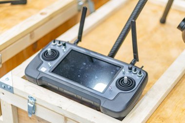 Beyaz düğmeli, ekranlı, iki kumandalı ve antenli ahşap bir tezgah üzerinde Ukraynalı FPV drone kontrolörü Endüstriyel ortamda doğal gün ışığı