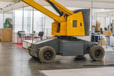 Beton zemin, beyaz tavan panelleri, metal çerçeveler, forklift, palet, gri modüler depolama ünitesi, tepe lambalarından yapay ışıklandırma.