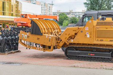 Beton üzerinde sarı bir tırtıl buldozer, büyük raylar ve itme bıçağıyla donatılmış, muhtemelen inşaat alanında ya da makine deposunda. Doğal gün ışığı, yakınlarda kimse yok.