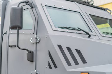 Gri siyah zırhlı mayın temizleme aracı, çoklu pencereli, koruyucu ızgaralar, açık hava ayarları, bulutlu ışıklandırma, yol arka planı, insan ya da metin yok, açık fotoğraf tarzı