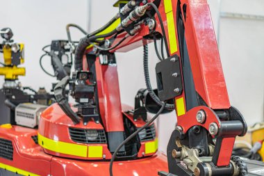 Sarı tabanlı endüstriyel robot, mekanik bileşenleri olan kırmızı kol, muhtemelen montaj hattının bir parçası. Sol üst köşeden yapay ışıklandırma, endüstriyel makinelere odaklan.