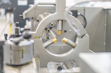 Endüstriyel makine metal bileşenlerine yakın plan, kapalı bir ortamda dairesel şekil, sol üstten aydınlatma, bulanık arka plan