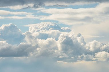 Pofuduk kümülüs bulutlarıyla kaplı bulutlu gökyüzü, gri ve beyaz gölgeler, bulutlardan yayılan ışık, görünür nesneler veya insanlar yok, doğal stil, hava perspektifi