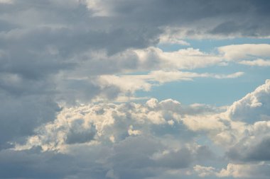 Kümülüs ve stratus oluşumları da dahil olmak üzere çeşitli bulutlarla kaplanmış gökyüzü, doğrudan gölgeler olmadan katmanlı bir etki yaratarak, sahnenin yükseltilmiş bir perspektifini gösterir.