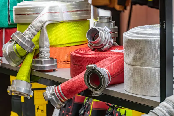 Yangın söndürme ekipmanlarının kapalı bir atölye atölyesinde bir depo rafına yerleştirilmesi birden fazla çıkış nozülü, bağlanabilir bölümlü ve metal teçhizatlı kırmızı yangın hortumları yerleştirilmesi