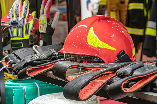 İş yerinde itfaiyeci ekipmanı aranjmanı kırmızı ve siyah itfaiye eldivenleri, miğferler, raflarda koruyucu gözlük, parlak ışık, sağ alt köşede yeşil branda