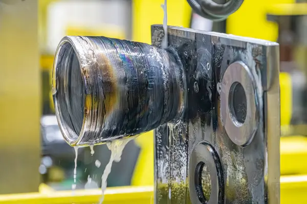 Endüstriyel bir ortamda kısmen batık silindirik metal bileşenine yakından bakınca, arka plan, otomatikman ve vites gibi hassas mekanizmaları gösteriyor.