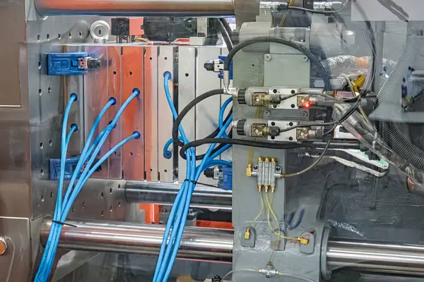 Sanayi sahnesi, büyük ihtimalle seri üretim için kullanılan N tipi bir fabrika ortamında klempleme mekanizmaları, hidrolik bileşenler, mavi kablolar ve sarı borular içeren büyük bir metal matbaayı gösteriyor.