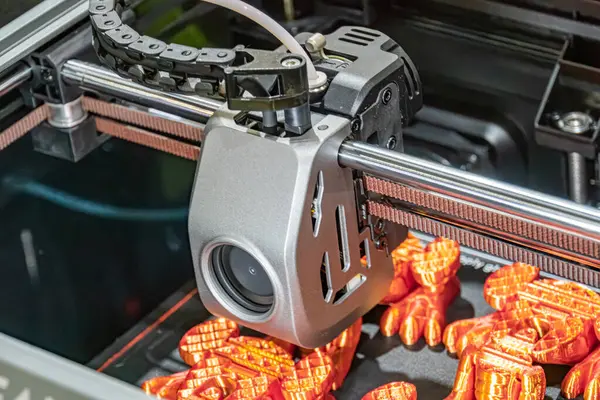 Taşıyıcı bandın üzerinde robotik bir kol bulunan turuncu renkli bir endüstriyel işlemin yakın plan görüntüsü taşıyıcıdaki nesneler küçük, muhtemelen küresel ve hareket eden makineler metalik zeka içeriyor.