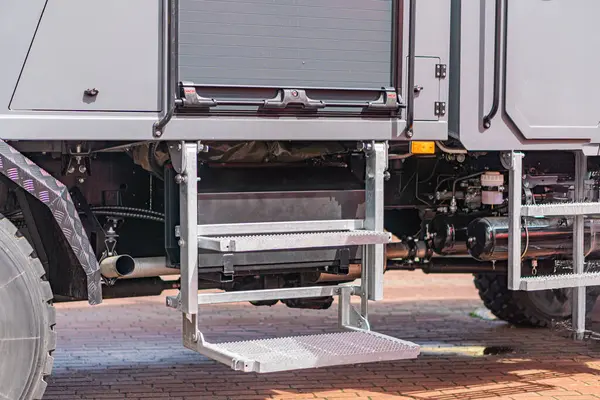 Gri ve siyah bir buldozer, yukarıdan görüldü, bir tuğla kaldırım üzerinde parkedilmiştir. Makinenin zırhlı dokuları vardır.