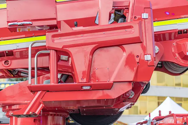 Kapalı alanda birden fazla eklemli kolu olan büyük kırmızı endüstriyel araç merdiven ve çeşitli eklentiler içeriyor, görülebilir borular ve eklemlerle hidrolik olarak güçlendirilmiş Diffused Lig