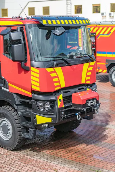 Tuğla kaldırıma park etmiş kırmızı itfaiye aracı, çoklu acil durum ışıkları, büyük tekerlekler, ızgara, potansiyel vinç sistemi veya eklenti noktası, doğal gün ışığı.