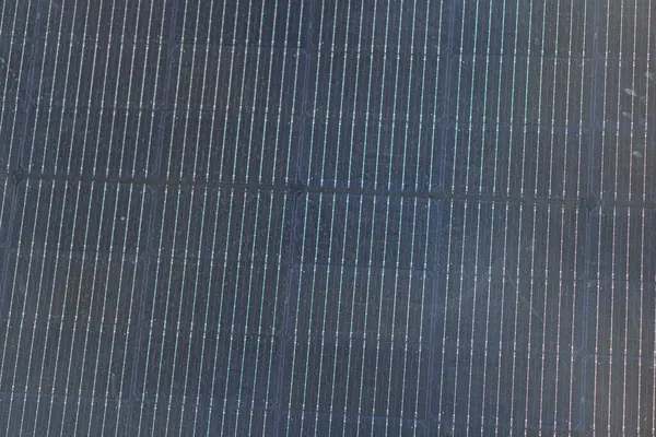 Büyük bir açık hava yapısının düşük açılı fotoğrafı koyu dikey parmaklıklar, ağ dokusu ve daha açık yüzeyi muhtemelen bir çit ya da bölme aydınlatması öğleden sonra geç saatlerde metin haliyle