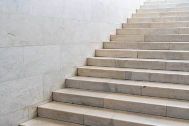 Gri ve bej renklerin farklı tonlarında yükselen mermer merdiven, bireysel adımlarla iyi korunmuş, iç planda bulanıklık, muhtemelen bir koridor, mevcut insan yok.