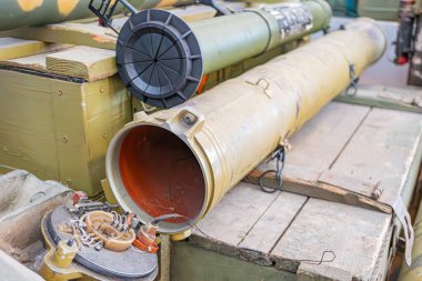 Görüntü, iki silindirli ve daha küçük silindirli bir endüstriyel depolama sahnesini tasvir ediyor. Büyük tank grimsi yeşil, sağlam ve üzerinde bir çıkıntı var. Olay yeri iyi aydınlatılmış ama unifo değil.