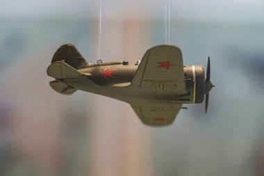 İkinci Dünya Savaşı döneminden kalma Sovyet uçak modelinin yer aldığı minyatür savaş sahnesi, yumuşak ışıklandırılmış arka planda kırmızı yıldız işaretleriyle asılı duruyor.