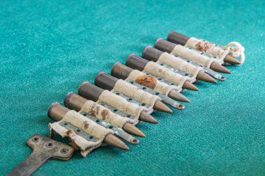 Mermi kovanlarının yatay dizilimi muhtemelen yeşil kumaş üzerinde, yumuşak tepeden aydınlatma altında mermiler şeklinde. a