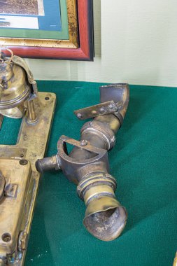 Antik pirinç bir objeye yakın plan, karmaşık bir tasarım, lekelenmiş ve hasarlı, yeşil bir arka plana karşı. a