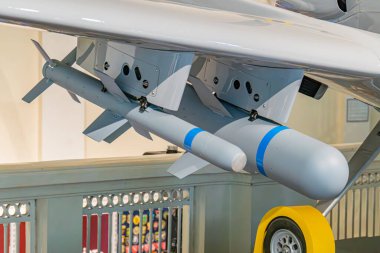 Ukrayna 'daki bir hangarda İHA görüntüsü, koyu renk şeması, genişletilmiş kanatlar, göbeğinin altında füze benzeri silahlar yukarıdan ve yandan yapay ışıklandırma.