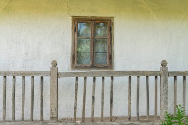 Orta Avrupa 'nın verandasında eski, beyaz, yıpranmış ahşap bir ev, elmas desenli pencere, kapalı panjurlar, doğal yeşil zemin, bastırılmış ışıklandırma, mevcut insan yok.