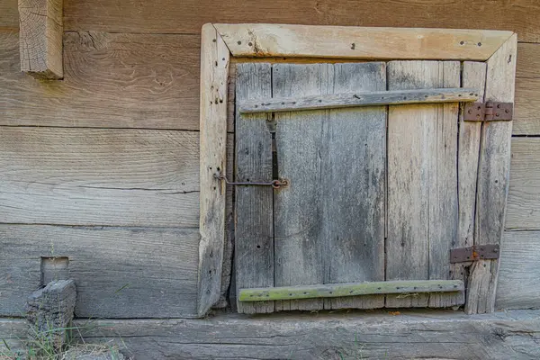 Eski Orta Avrupa köyünde kırsal kesimlerde aşınmış ahşap kapı, doğal aydınlatma, toprak tonları, insan aktivitesi yok