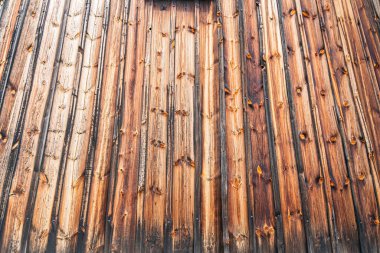 Yıpranmış ahşap bir yapının yakın çekimi, muhtemelen eski bir kilise kiremit ya da slat, organik tortu ile sıcak renk paleti, kahverengiler ve siyah benekler içeren bulutlu gün veya arka plandaki görüntü Elevat