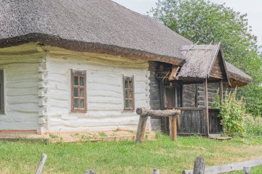 Koyu kahverengi kiremitleri, birden fazla penceresi, kepenkleri, sağlam ahşap kapısı, çimen ve bitkilerle çevrili küçük bir çitli alanı olan eski, Orta Avrupa köyü.