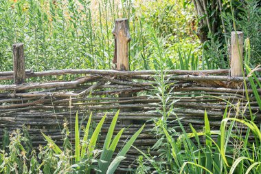 Orta Avrupa 'da bir köyün taşralı manzarası. Çapraz çizgili ahşap bir çit, yemyeşil ve canlı renklerle süslenmiş. Arkasında hiç kimse yok.