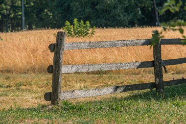 Kırsal, eski Orta Avrupa köyü manzarası berrak bir gökyüzünün altında kurumuş çimlerle kaplı açık bir arazide aşınmış ahşap bir çitin çapraz görüntüsü.