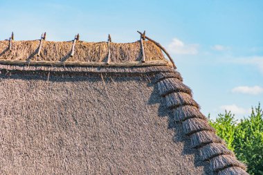 Antik Orta Avrupa sazdan çatı yapısı, toprak renkleri, bastırılmış renk paleti koyu kahverengi, açık mavi, öğleden sonra aydınlatma, gerçekçi tasvirler, doğal dokular ve renkler, insan ya da