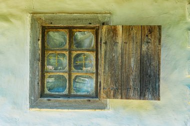 Eski, yıpranmış, eski bir Orta Avrupa köyünün ahşap penceresi. Soluk renk paletine dünyevi tonlar hükmediyor. Bina taştan yapılmış olabilir.
