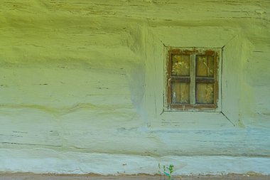 Orta Avrupa köyündeki eski sarı ev, soyulmuş boyalar, ahşap kepenkler, renkli camlar, solmuş duvarlar, potansiyel su hasarı, yumuşak dağınık ışıklandırma, izole edilmiş ayarlar, belgesel tarzı.