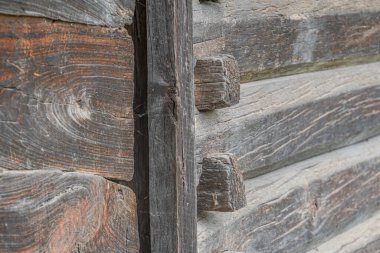 Orta Avrupa 'da bir köyde yaşlanmış, yıpranmış, ahşap bir yapının yakın çekimi. Görünür çürüme ve çürüme ile dikey yan yana, açık kahverengiler koyu bölgelere, yatay bantlarla inşa edilmiş. Yumuşak, dağınık aydınlatma.