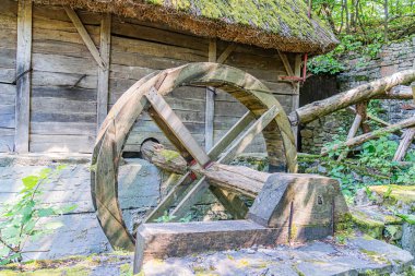 Kırsal Orta Avrupa köyü manzarası gür yeşillikte ahşap tekerlek ve taş duvar, yüksek perspektif, gündüz aydınlatma, canlı renkler