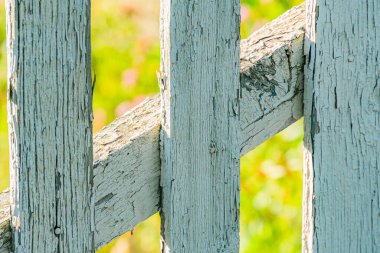 Orta Avrupa 'da bir köyde yaşlanmış, yıpranmış ahşap bir çitin yakın plan görüntüsü boşluklardan süzülür, yumuşak gölgeler bırakır ve odaktan çıkmış sıcak bir ışık, doğal bir torba olduğunu gösterir.
