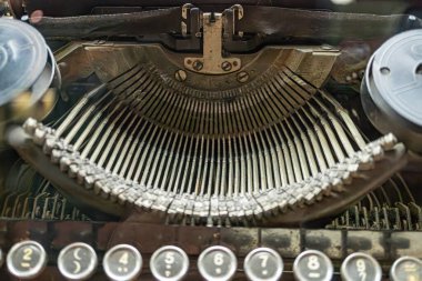 Antik daktilo klavyesinin yakın görüntüsü, QWERTY düzeni, renkli anahtarlar, insan eli yukarıda, hafif açılı perspektif. a